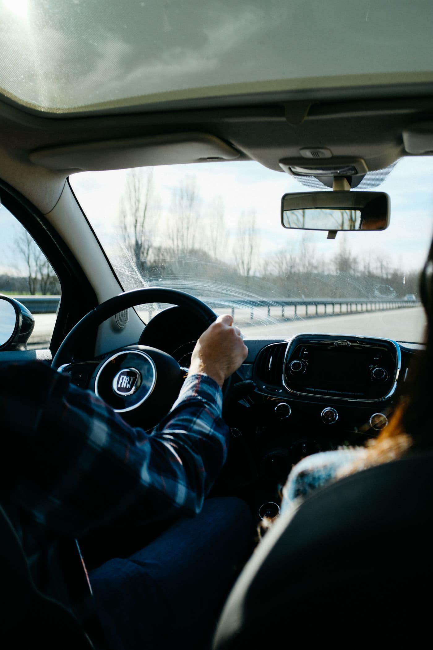 A driver at the wheel on a winter highway with a passenger beside them